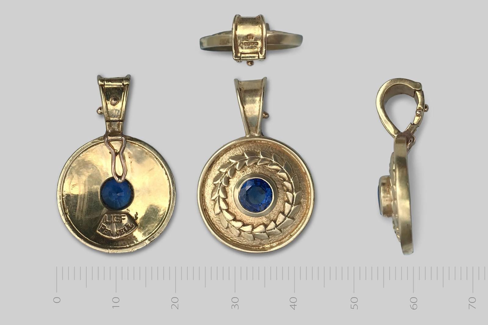 Gold pendant set with a blue sapphire, photographed from both sides beside a measuring scale